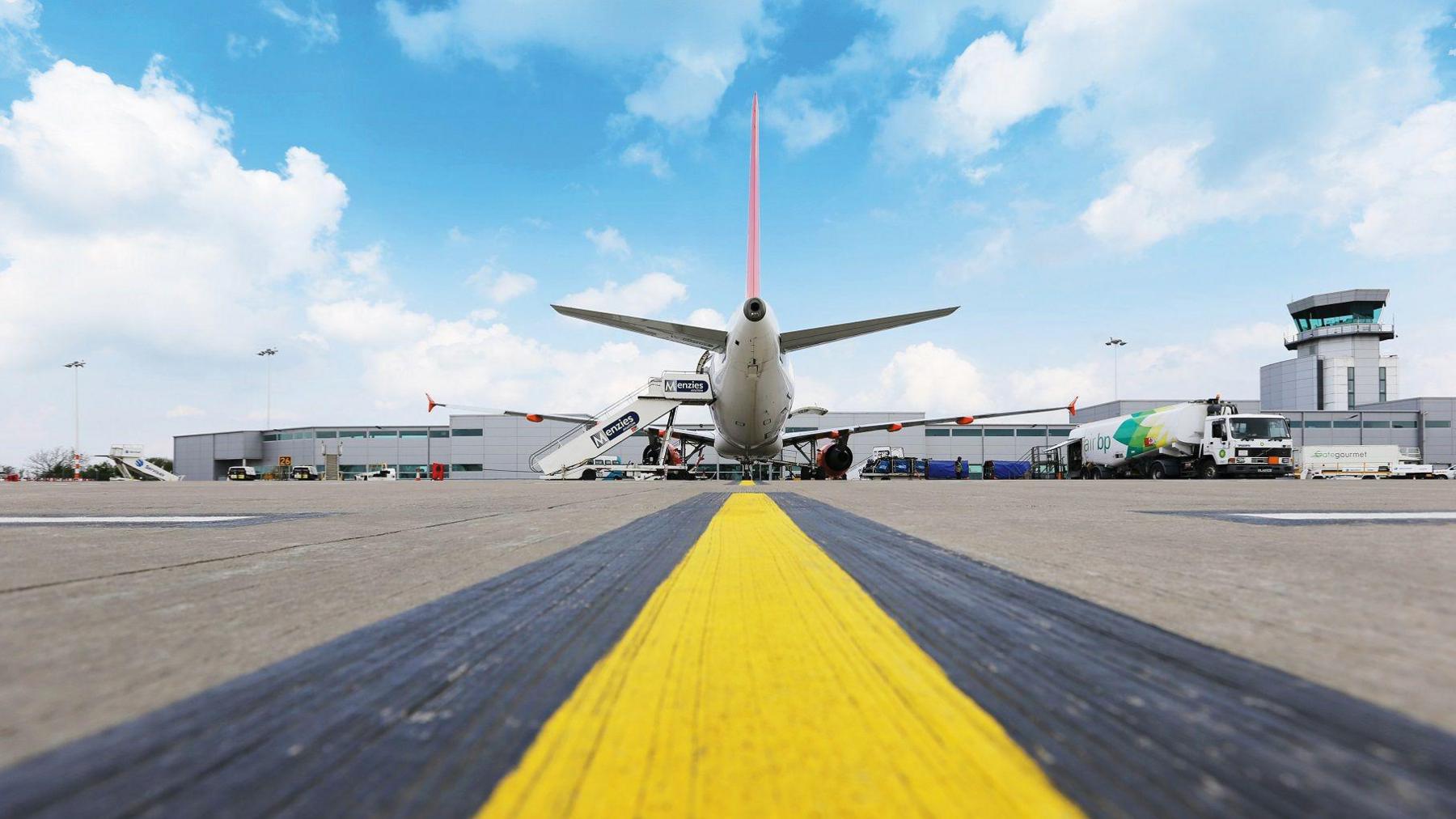 A wide view of a runway at Bristol Airport with an Easyjet plane visible in the background