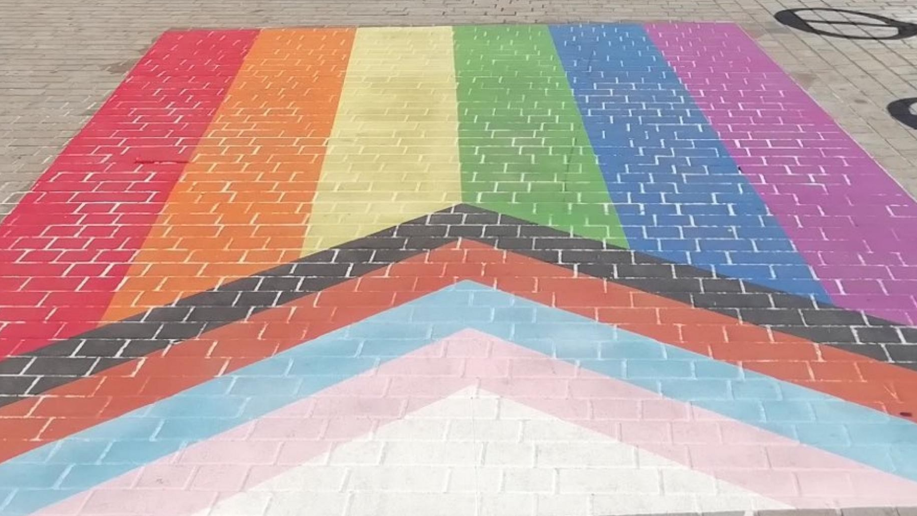 The multicoloured Pride flag on the pavement, before it was defaced