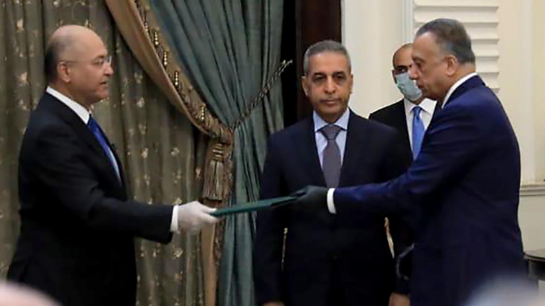 President Barham Saleh (L) and Mostafa al- (R) wore gloves at the ceremony