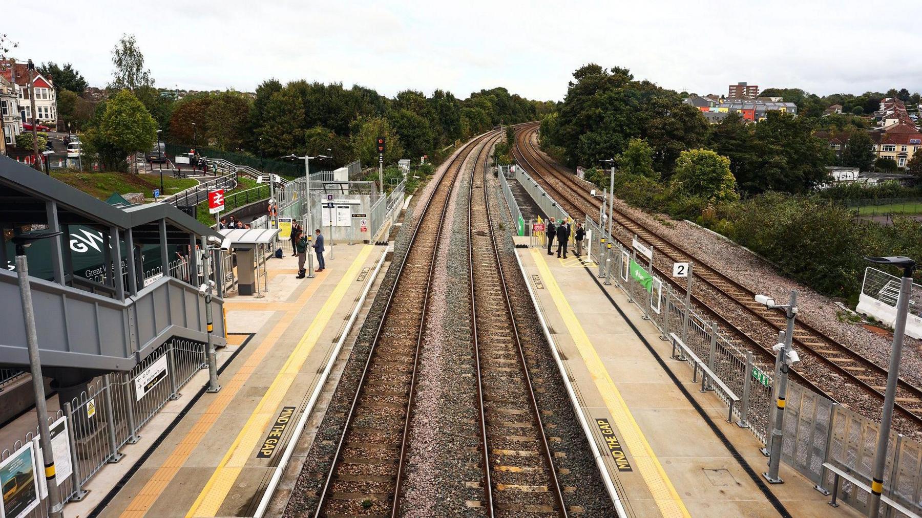 An aerial shot of the new Ashley Down train station in Bristol, showing both platforms and the double train tracks stretching off into the distance