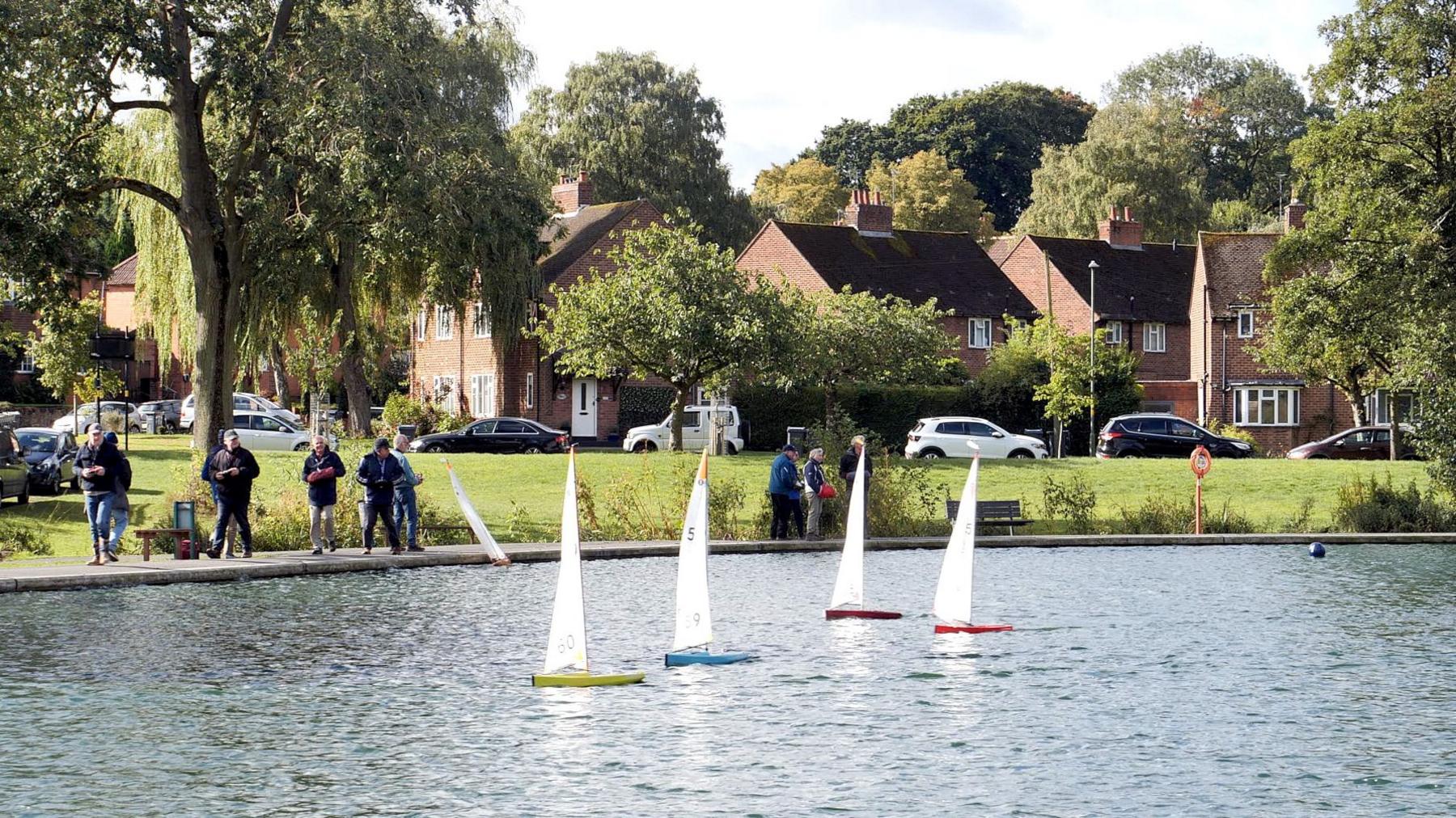 People on edge of lake with model yachts on the water