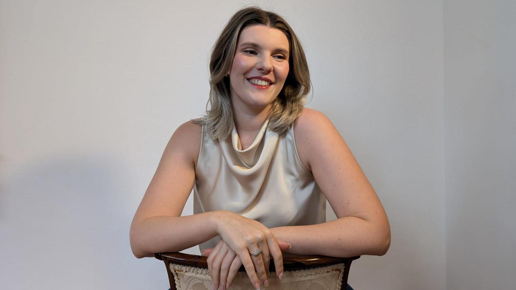 Jess Warren in a cream, sleeveless blouse, smiling and looking away from the camera.