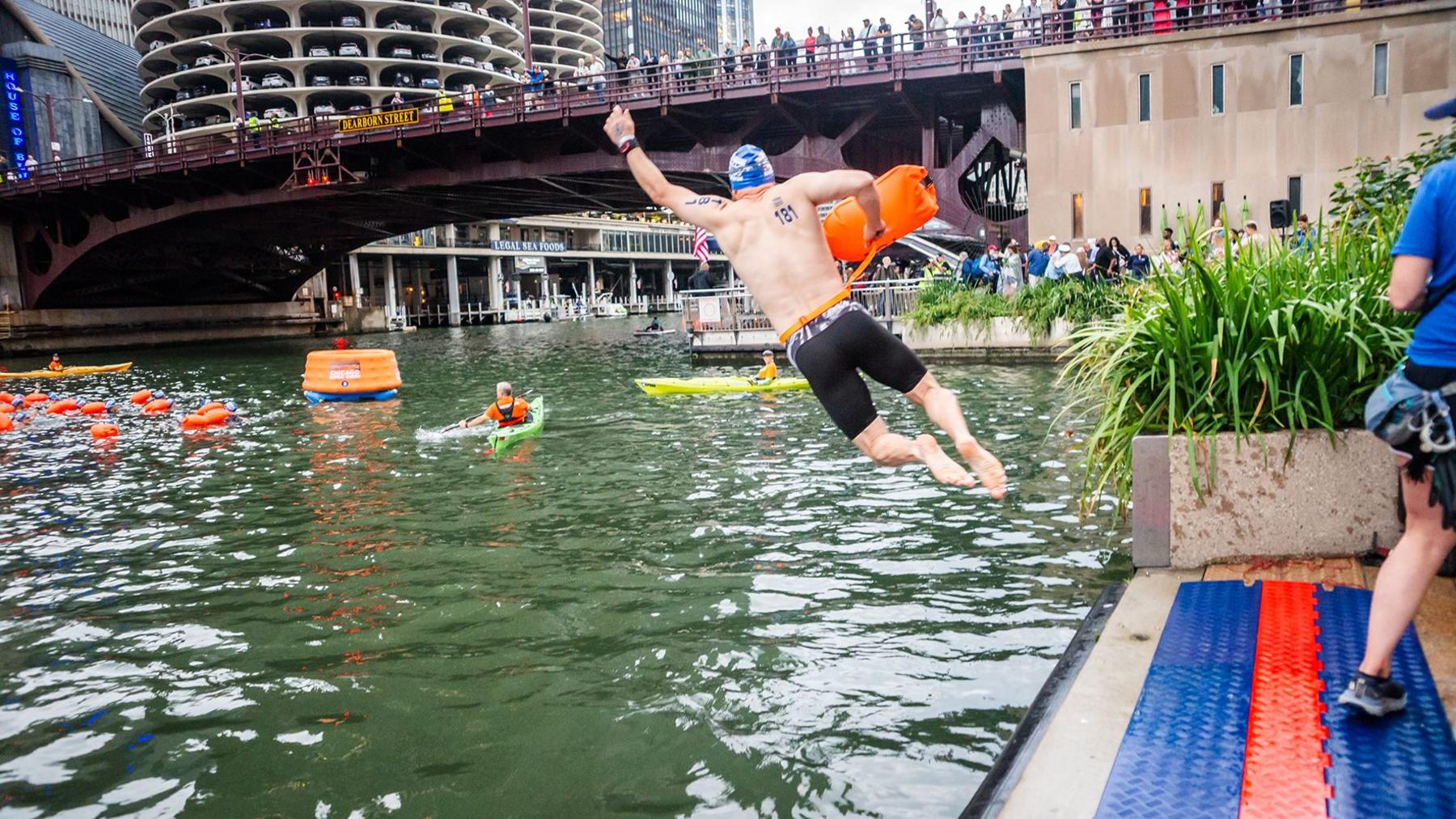 A man jumps into the water holding a float
