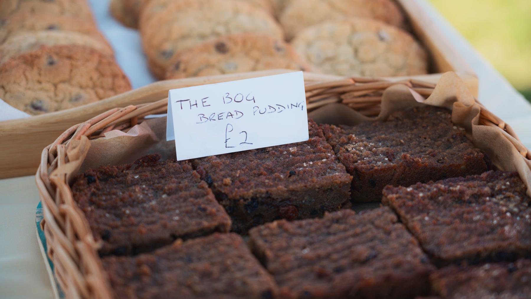 Bog bread pudding pictured in a rattan basket. A white paper label reads: The bog bread pudding £2. 