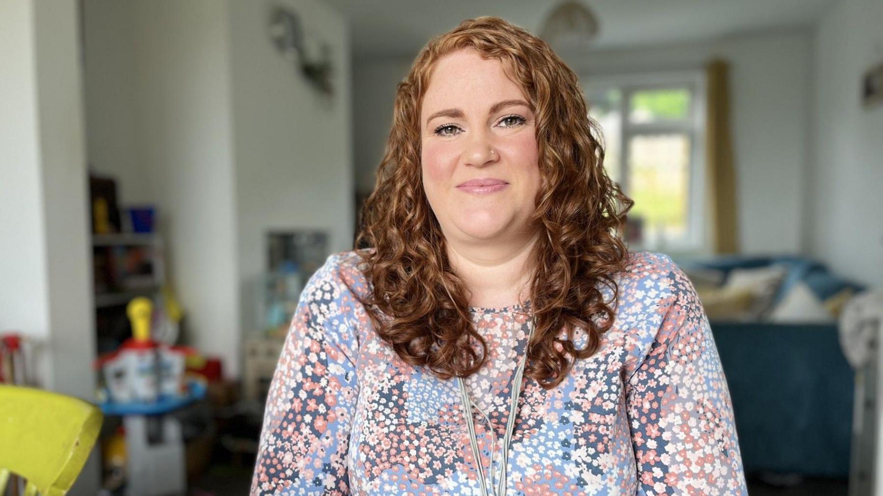 Red haired woman sits at a table in her living room