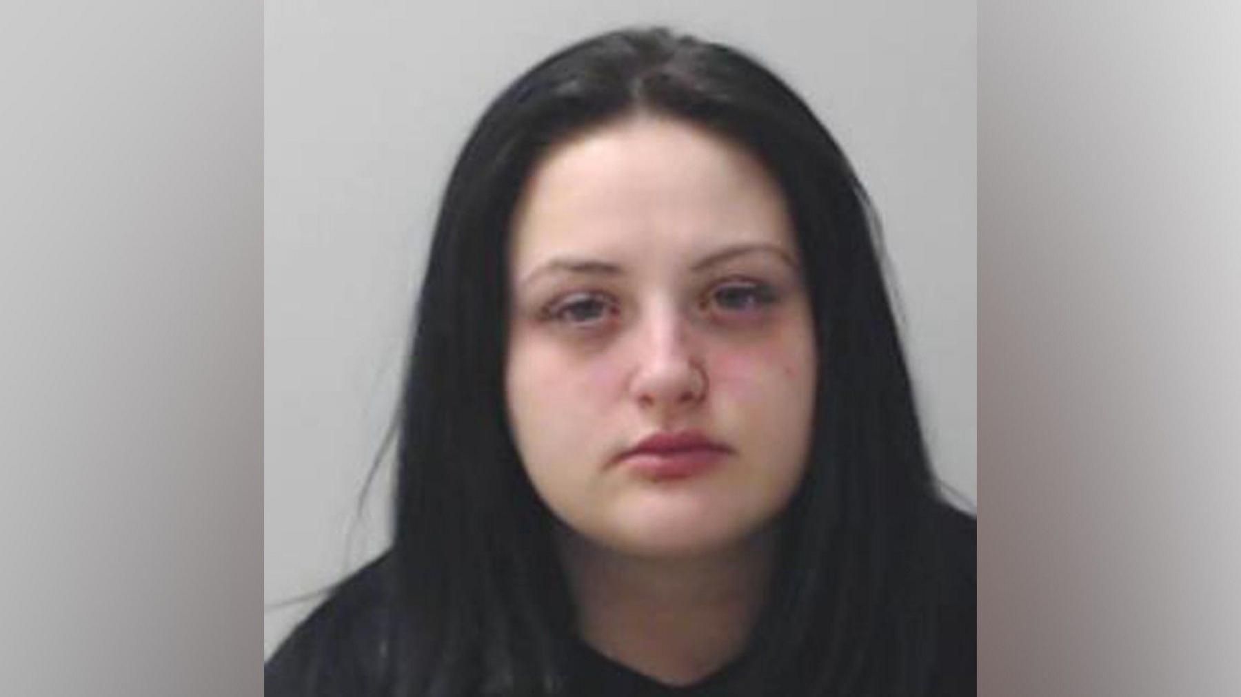 A mugshot of a young woman with long dark hair. 