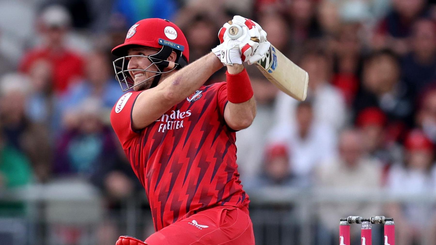 Liam Livingstone playing for Lancashire, hitting a shot down on one knee with his bat over his shoulder in the follow-through
