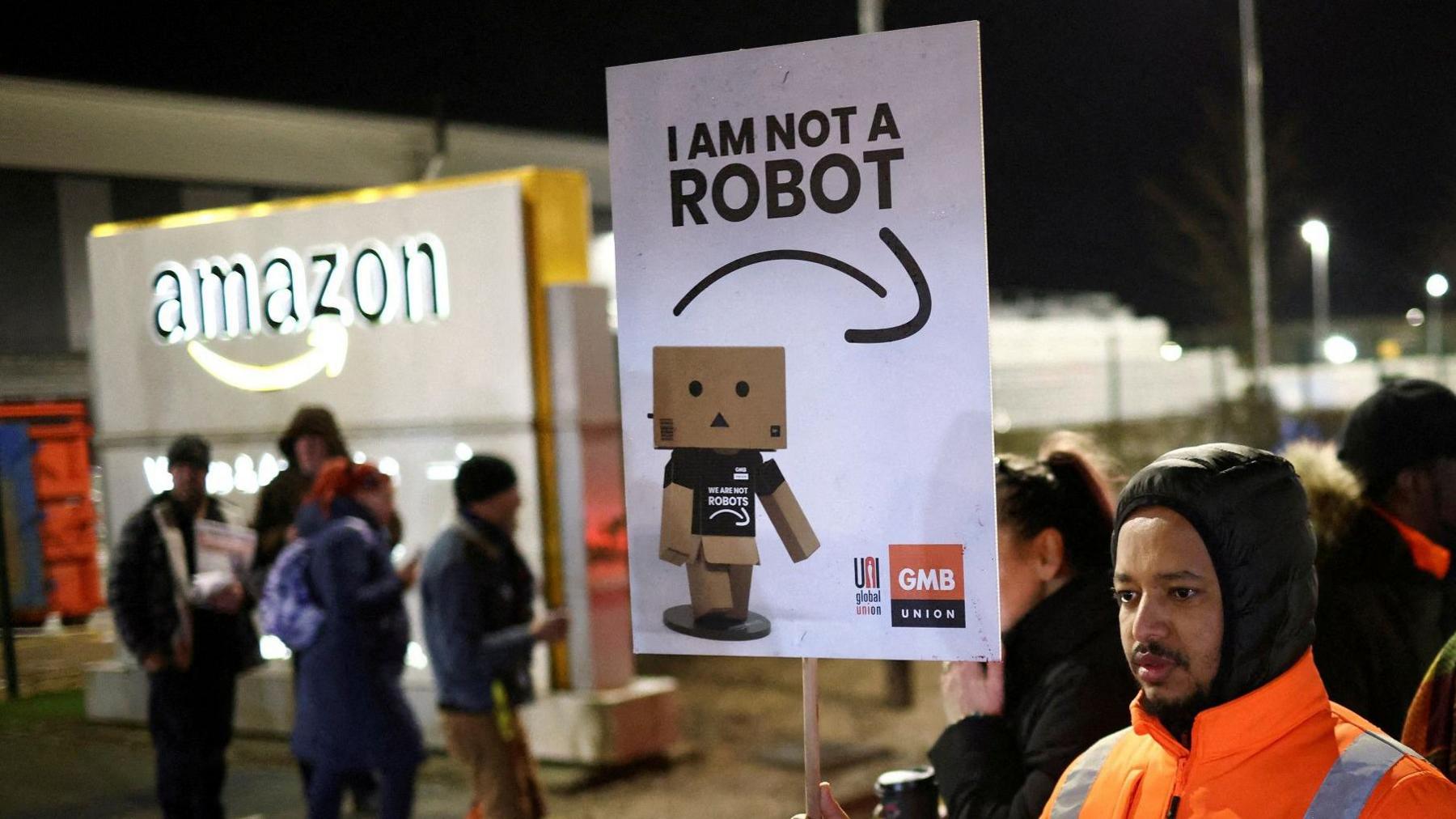 A man holds a sign saying "I am not a robot" during a previous rally in support of Amazon workers' on strike outside the Amazon warehouse in Coventry