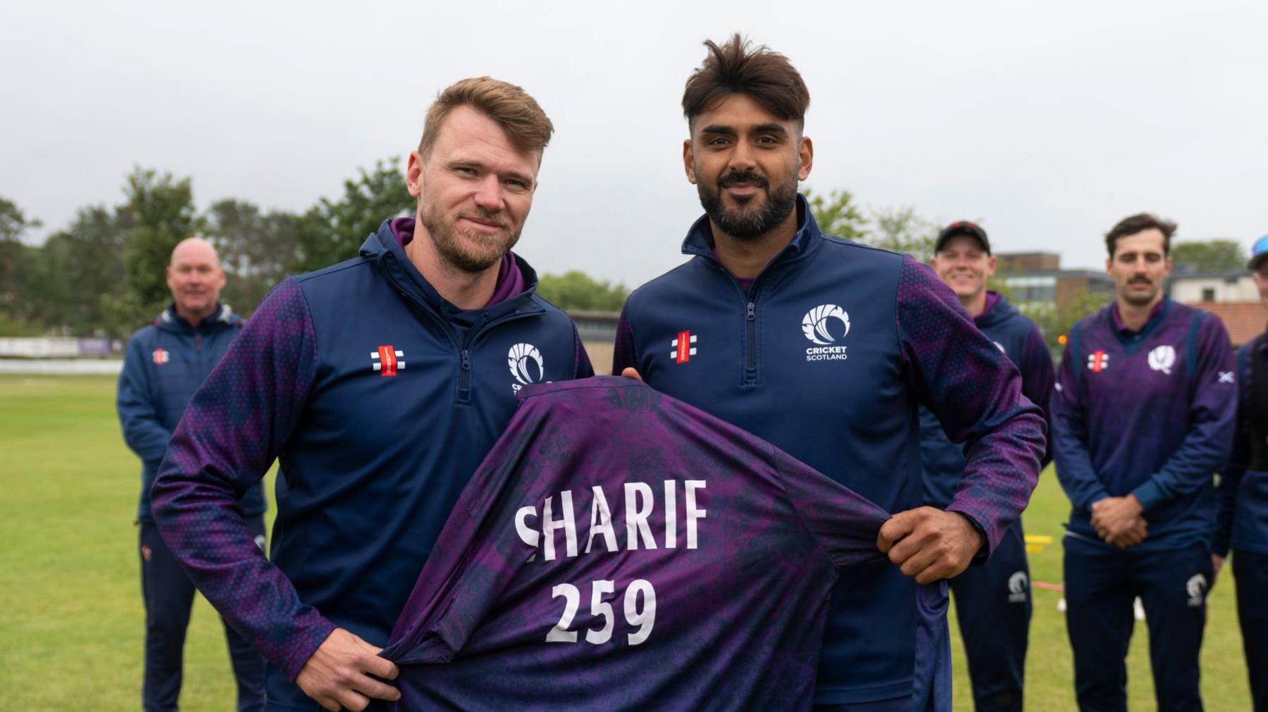 Richie Berrington poses for photos alongside Safyaan Sharif, holding a shirt with the number 259 on it