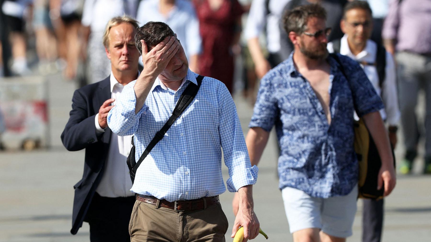 Commuters walk in the sun as they cross London Bridge , during a heatwave, in central London on June 24, 2026. The UK recorded its hottest ever June temperature on Wednesday with the mercury rising to 35.7C south of London, breaking the previous record of 35.6