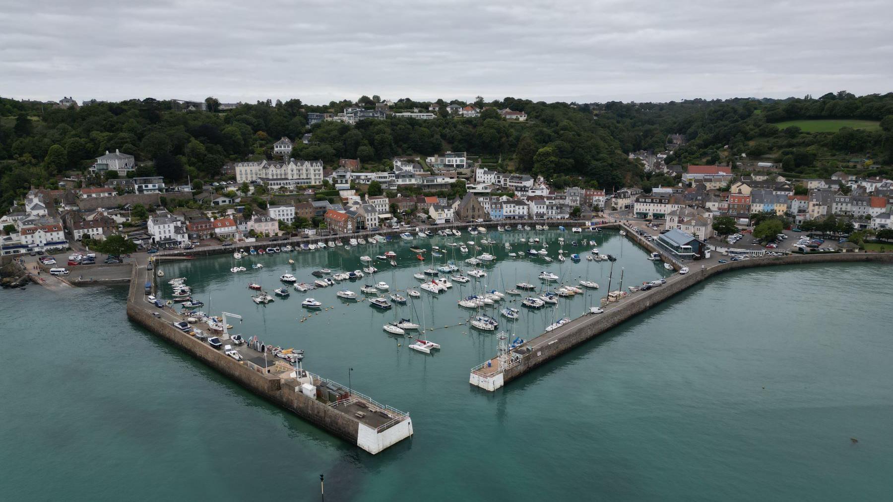 A small granite harbour at high tide, with boats in the harbour and a small village behind.