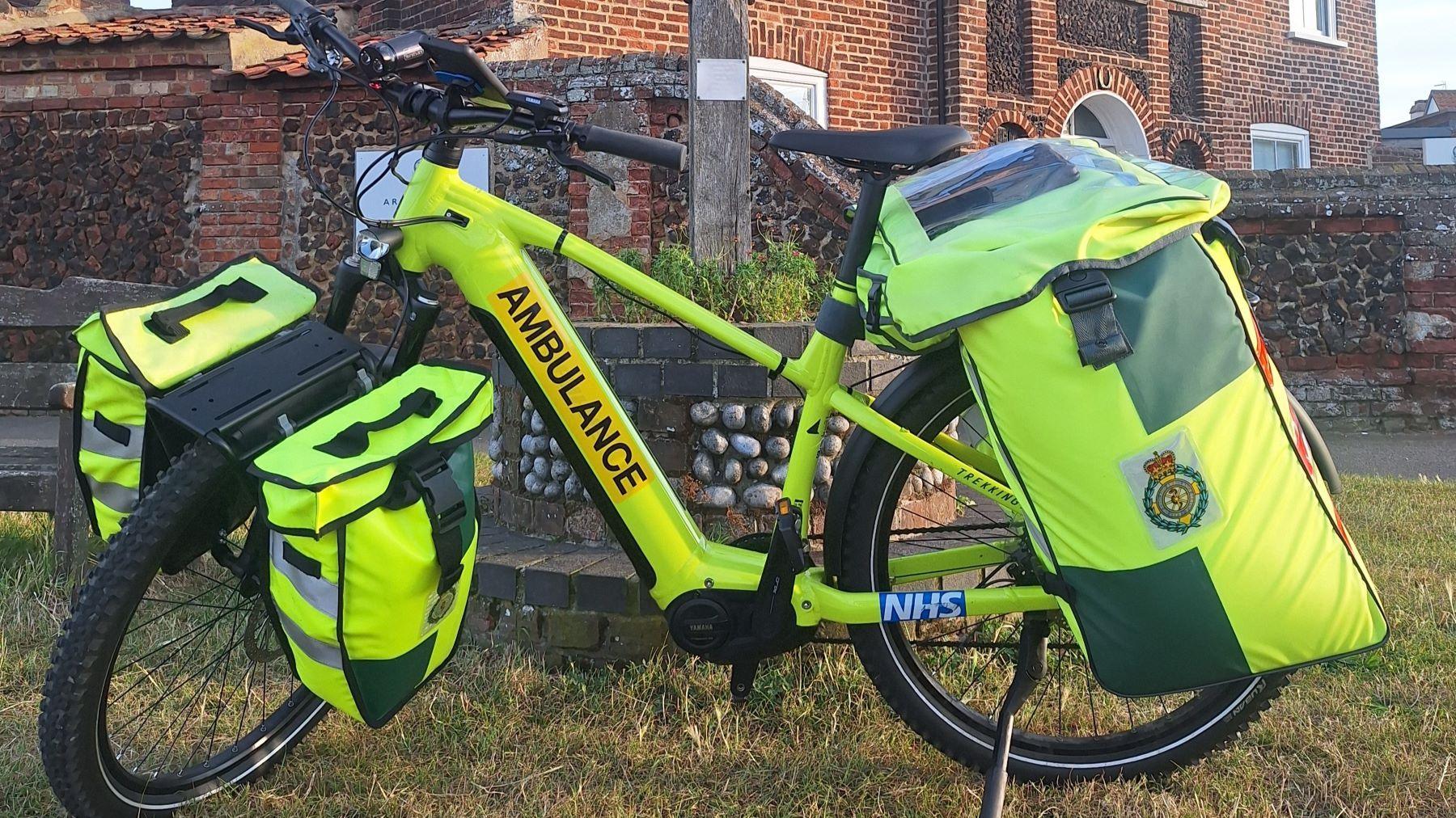 A high visibility e-bike which has the word "ambulance" on the side. It has panniers at the front of back.