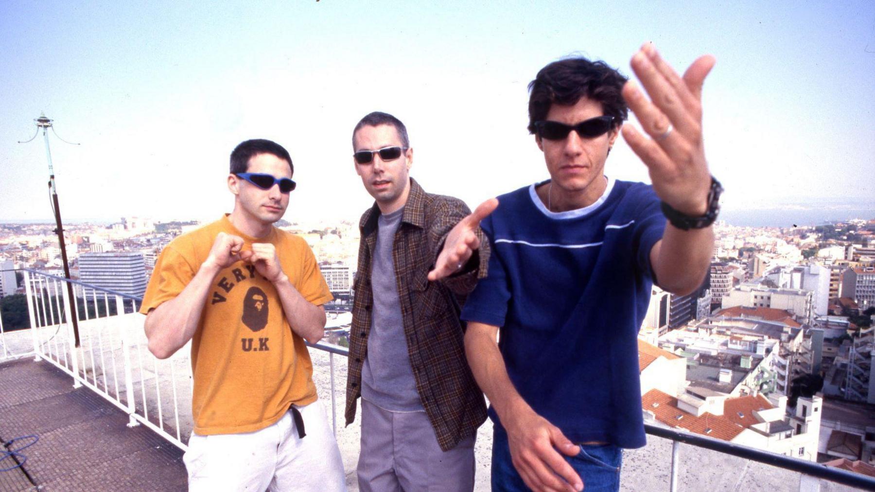 Beastie Boys in 1998 - the trio are on a balcony, reaching their hands out towards to the camera