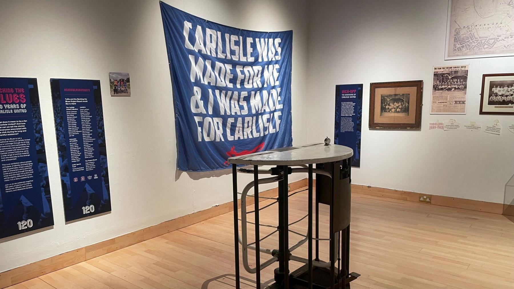 Large museum gallery room with football signs and information on the walls, including old newspaper clippings and maps.