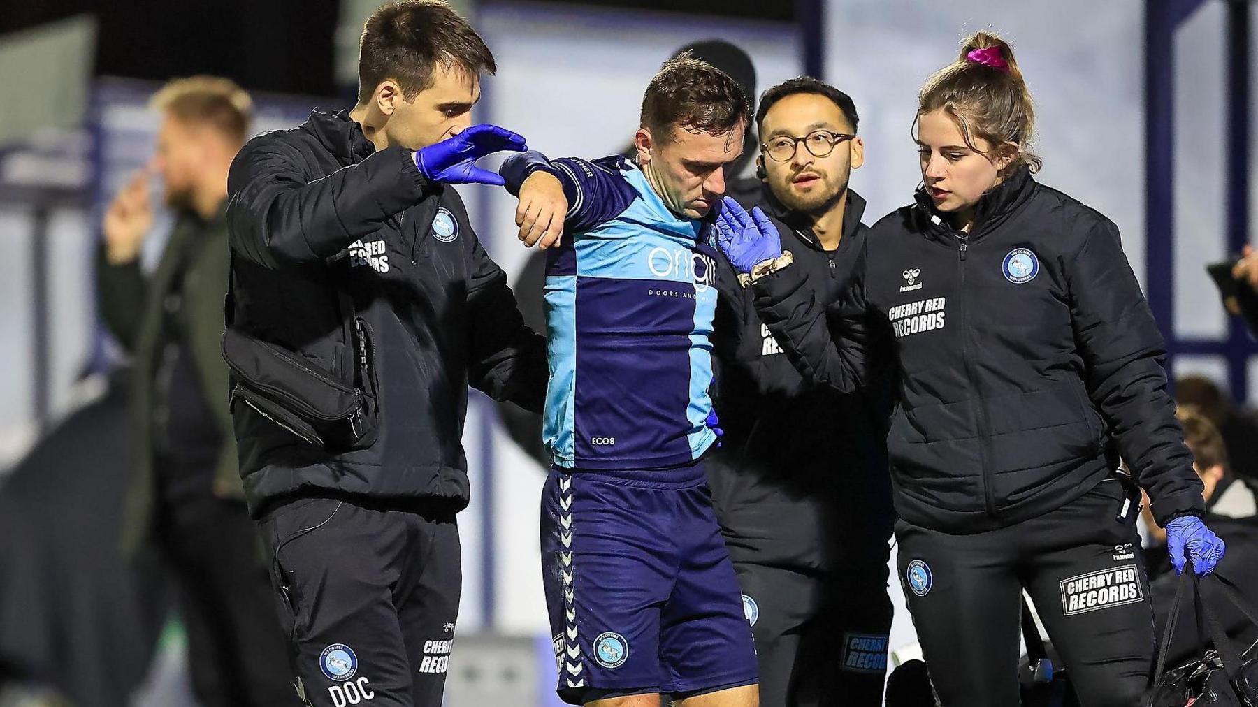 Wycombe Wanderers medical staff help Josh Scowen off the pitch after he suffered an injury against Crawley Town