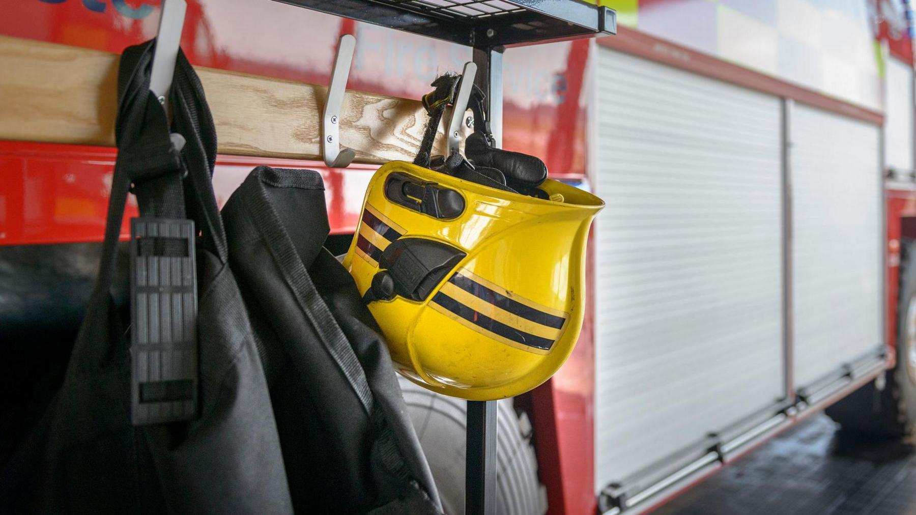 A Fireman's yellow helmet hanging by fire engine in a fire station.
