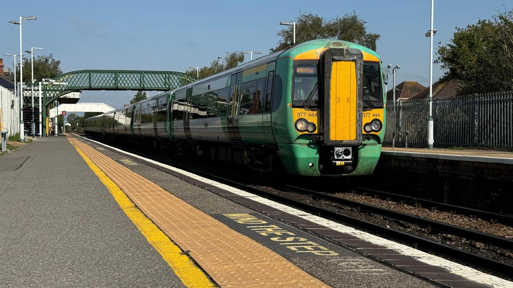 A green Southern Rail Bombardier Electrostar Class 377 awaiting to depart Hampden Park railway station in East Sussex, UK, for Eastbourne terminus.