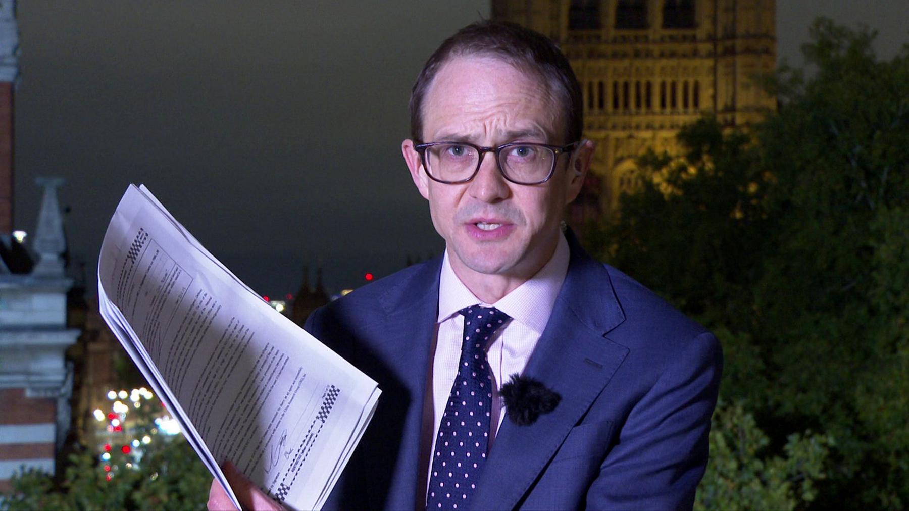 Chris Mason standing with the witness statements printed on a pile of paper in Westminster