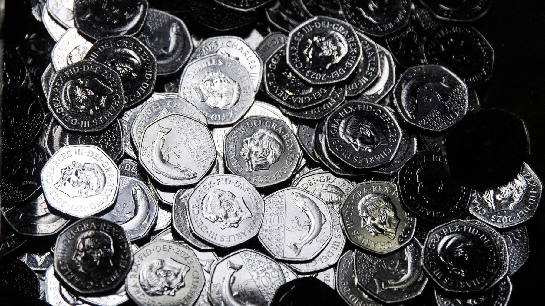 A huge pile of 50p coins with the Atlantic salmon on the reverse and King's portrait in the front. 