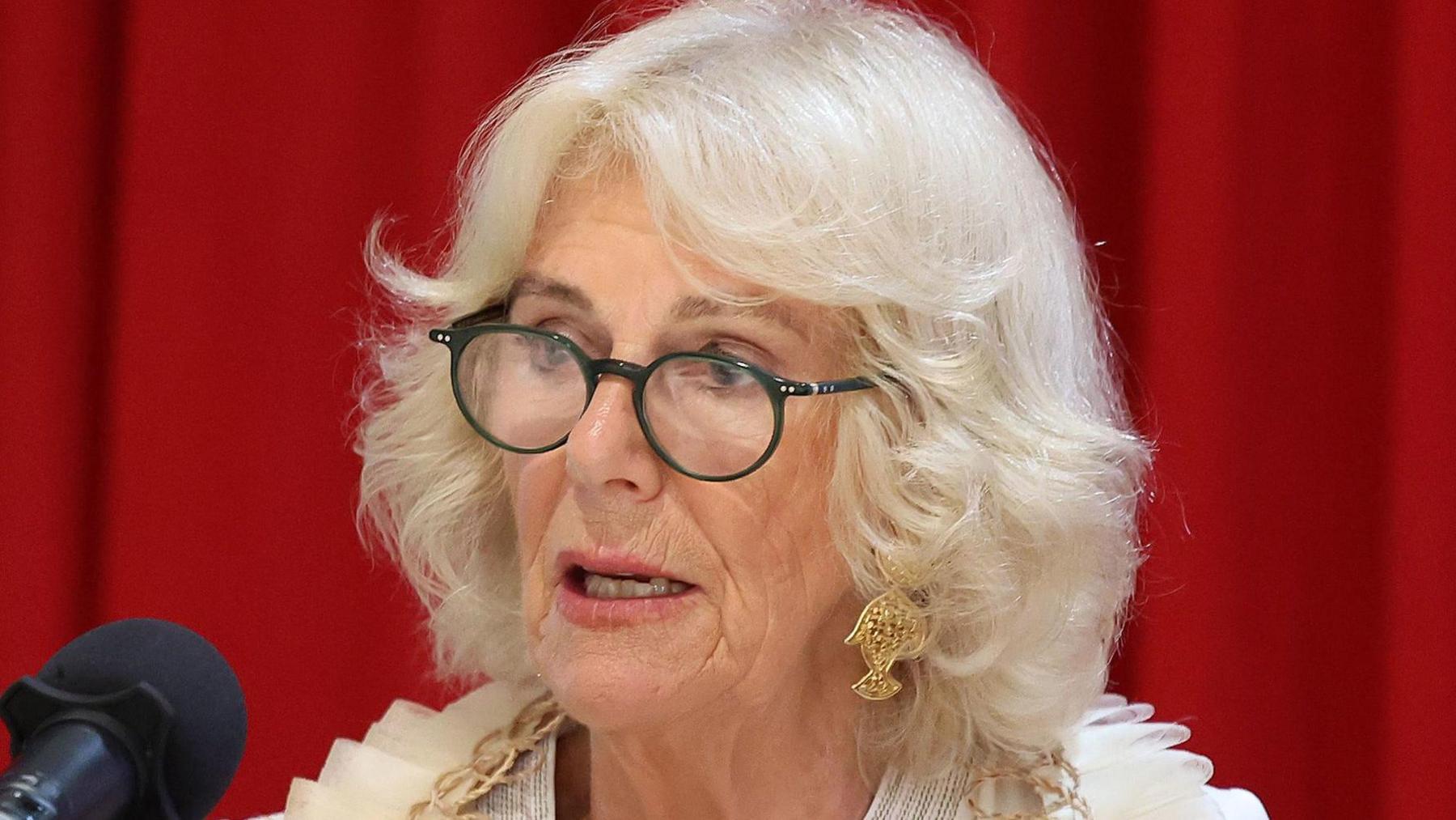 Queen Camilla, wearing glasses, speaking at a women's forum in Samoa