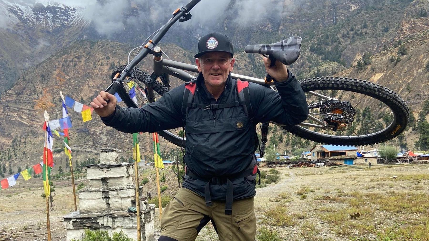 Neil Laughton carrying his bike on his back in the Himalayas.