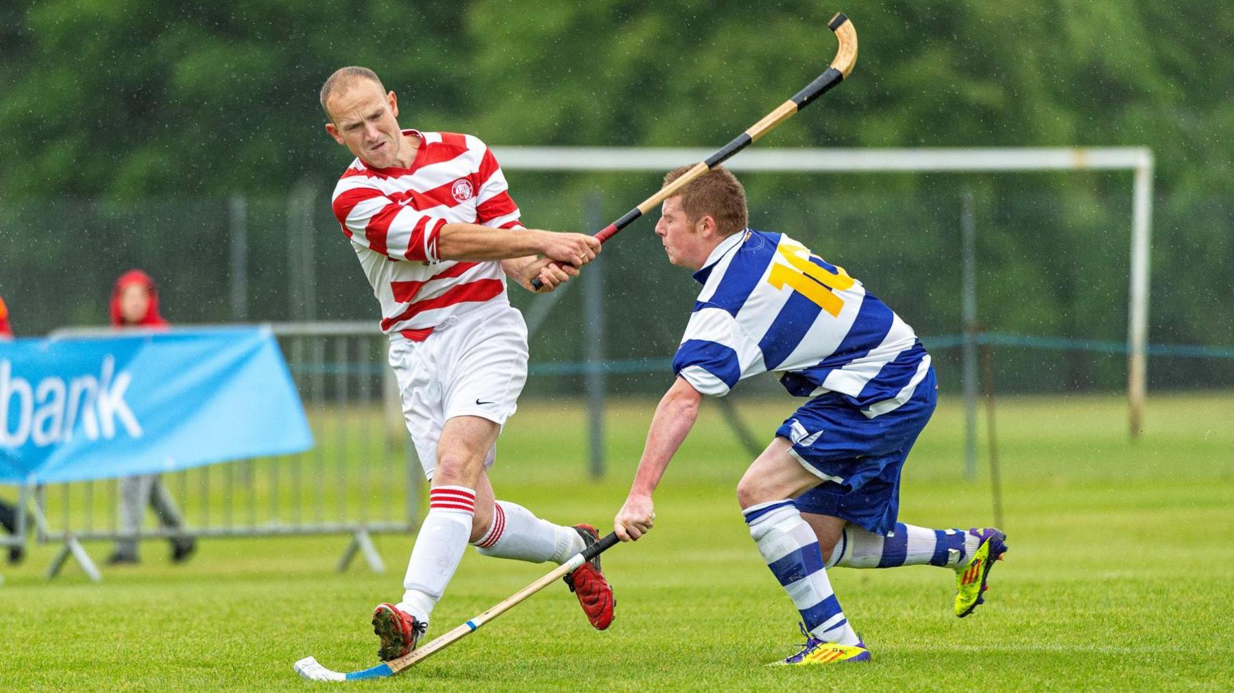 Lachlan, left, is running while striking a ball. An opposition player tries to put in a tackle.