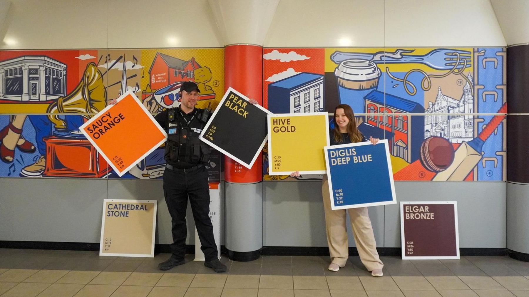 A man and a woman holding up colour palette boards