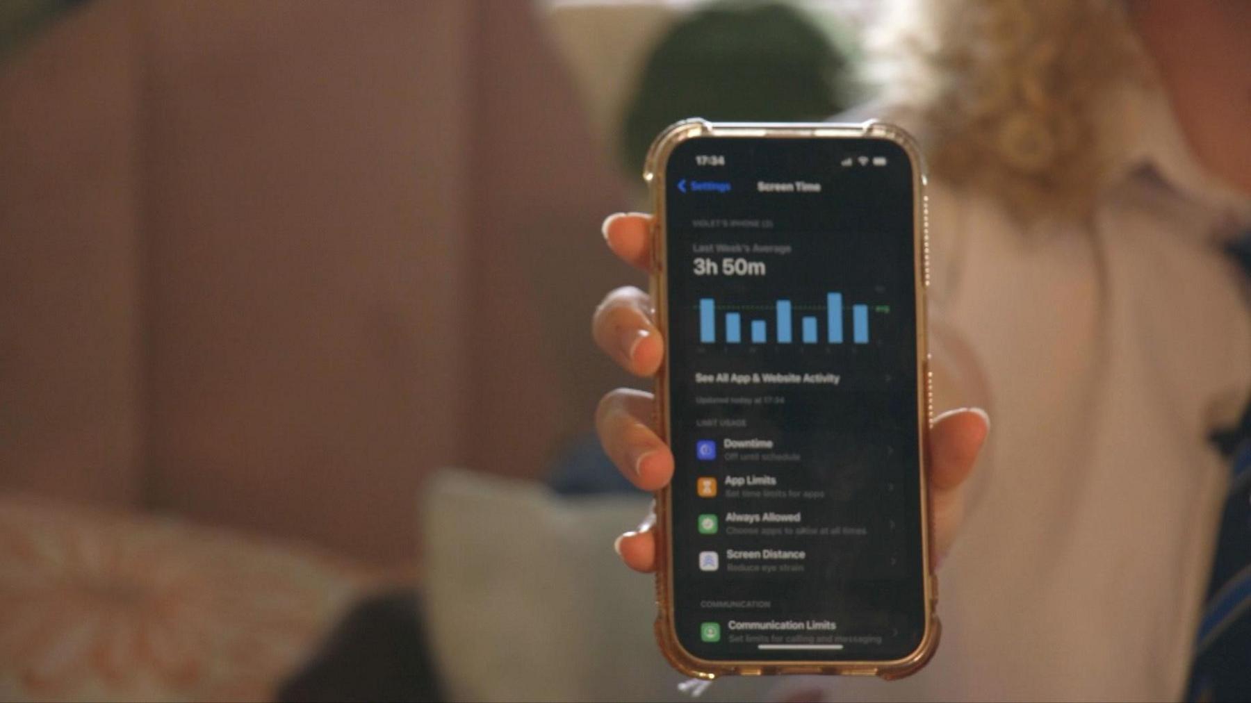 Violet holding up her phone, showing an average screen time of 3 hours 50 minutes