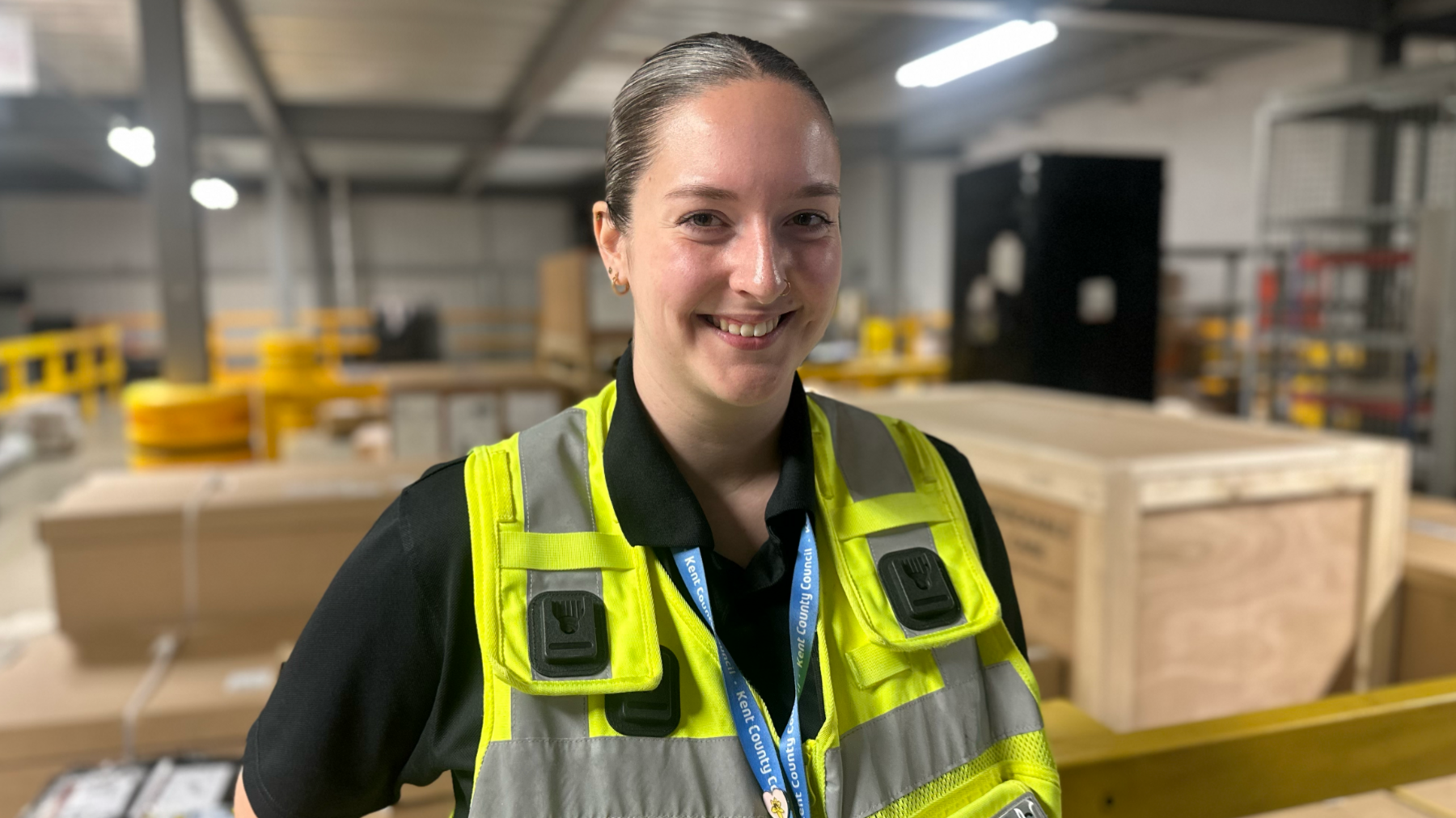 Beth Bushell standing in her high visibilty jacket in the middle of the parcel depot in Dartford surrounded by crates and boxes