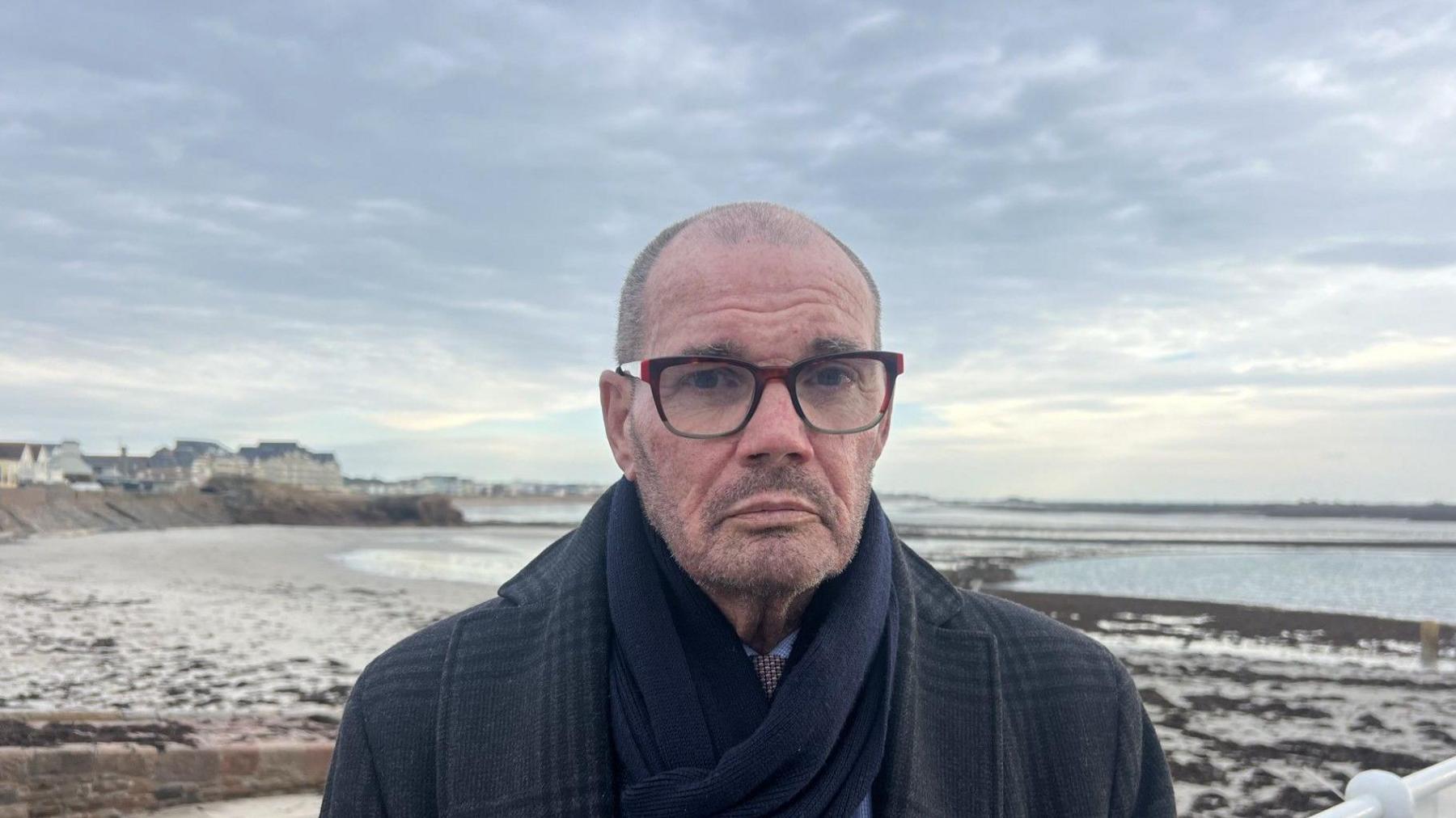 Constable Marcus Troy wearing a black coat and scarf and a blue shirt.