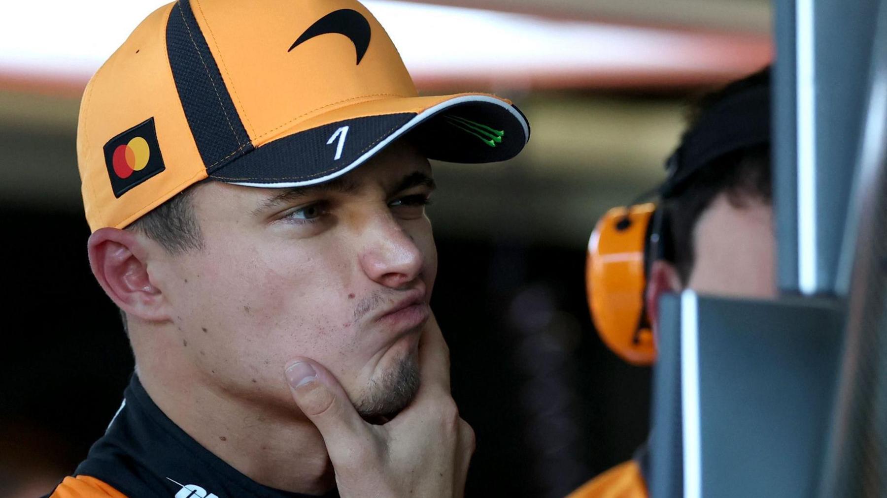 McLaren's Lando Norris strokes his chin and has a slightly puzzled look while studying a timing screen during Australian Grand Prix first practice