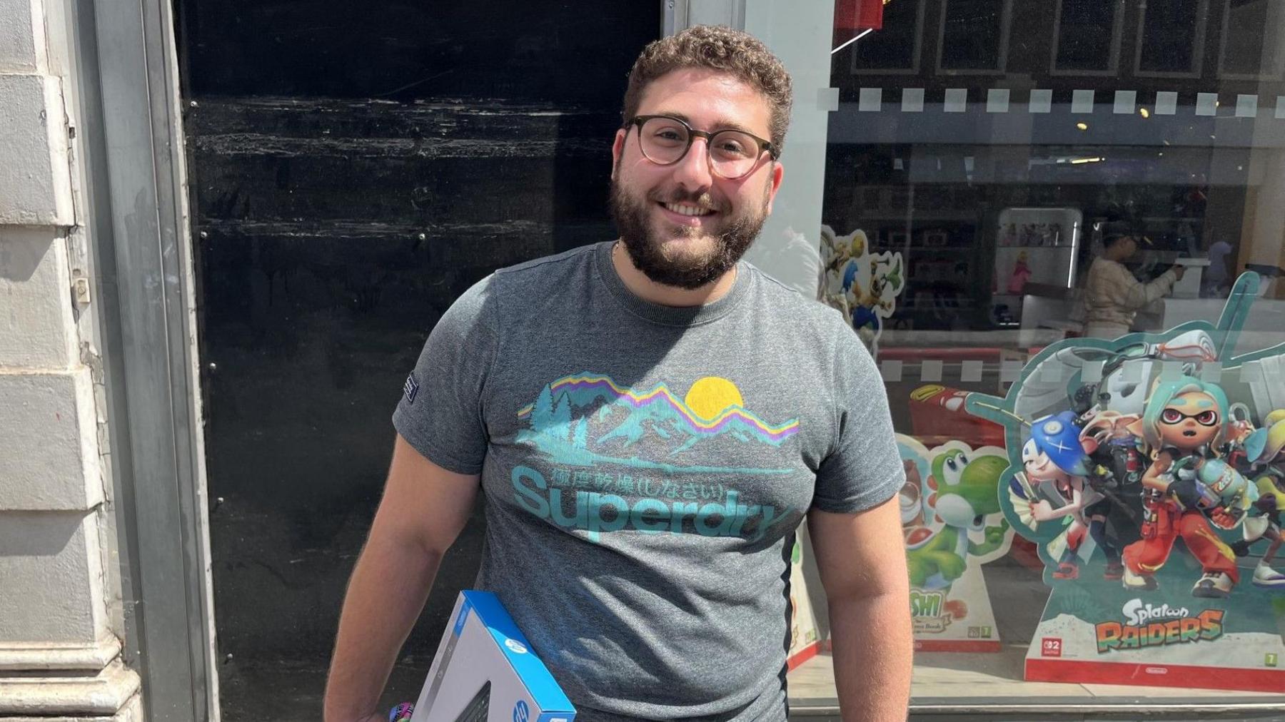 Enrico, 28, stands on a UK high street holding a parcel