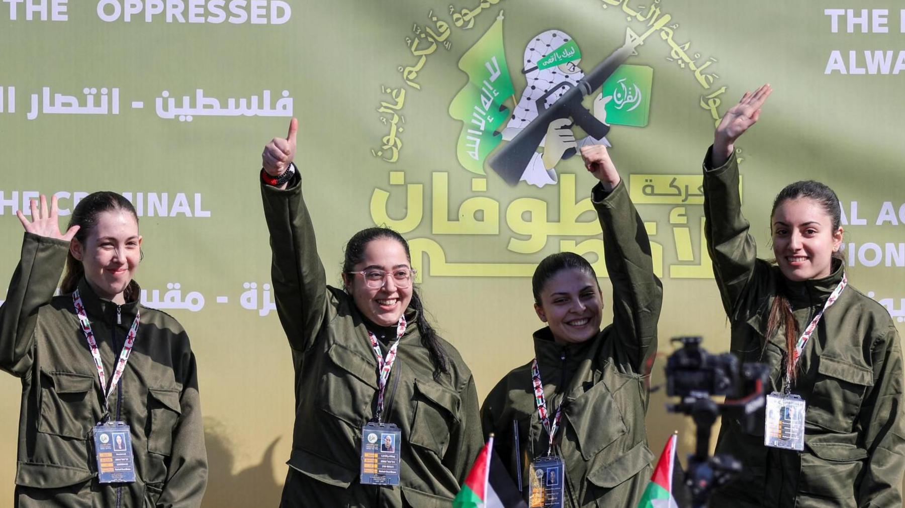 Four female Israeli soldiers, who were held in Gaza, wave from a stage as they are released by Hamas 