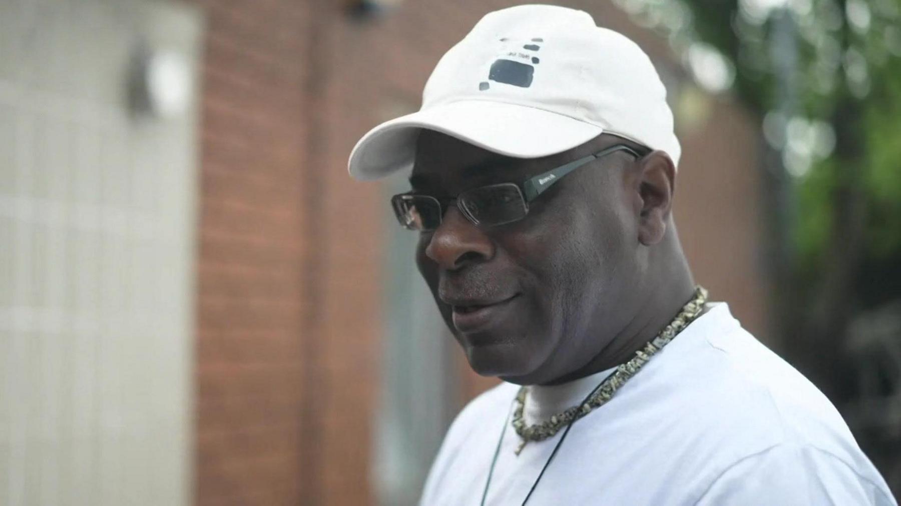 Man wearing white t-shirt and white baseball cap and glasses