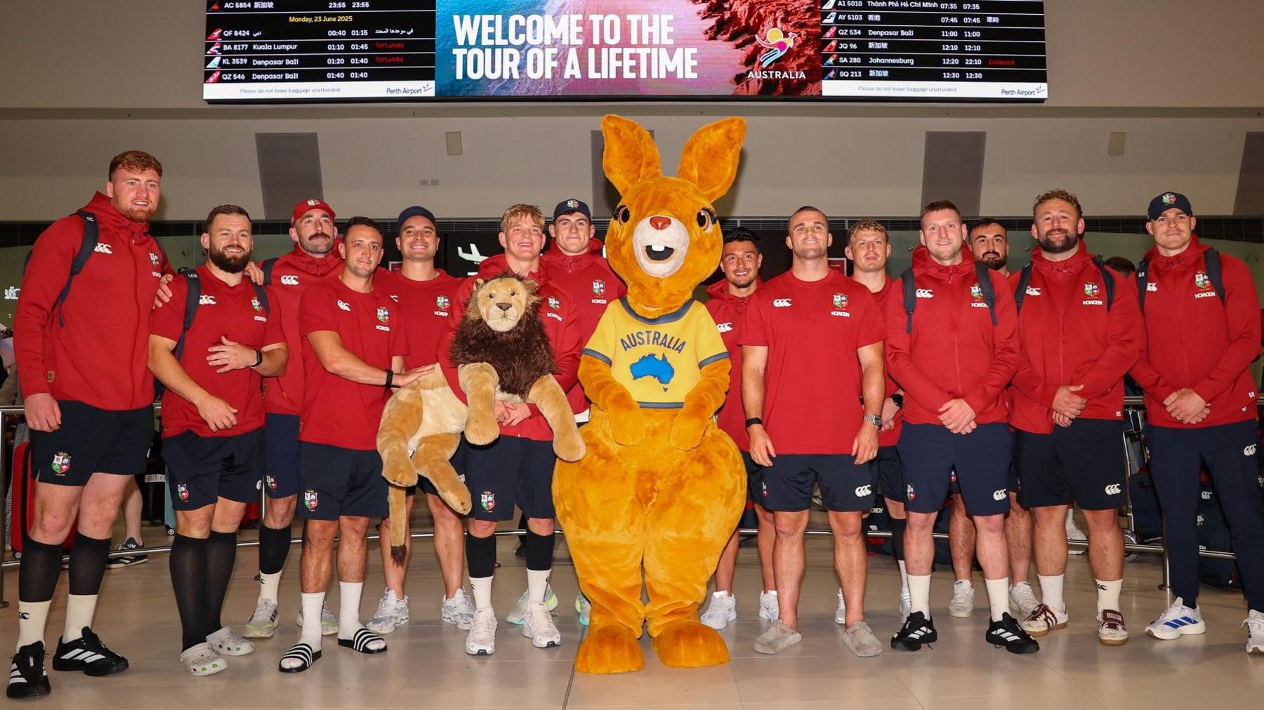 The Lions pose with mascot Bill the Lion and a person dressed in a kangaroo costume at Perth Airport