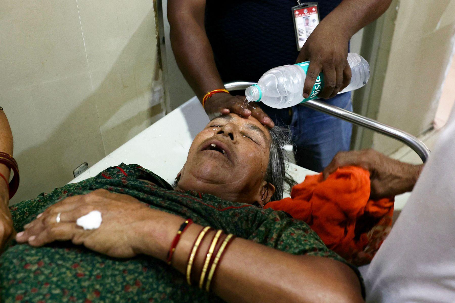 A hospital staff member pours water on the face of a patient suffering from heat stroke at a government hospital during a severe heatwave in Varanasi on May 30, 2024. 