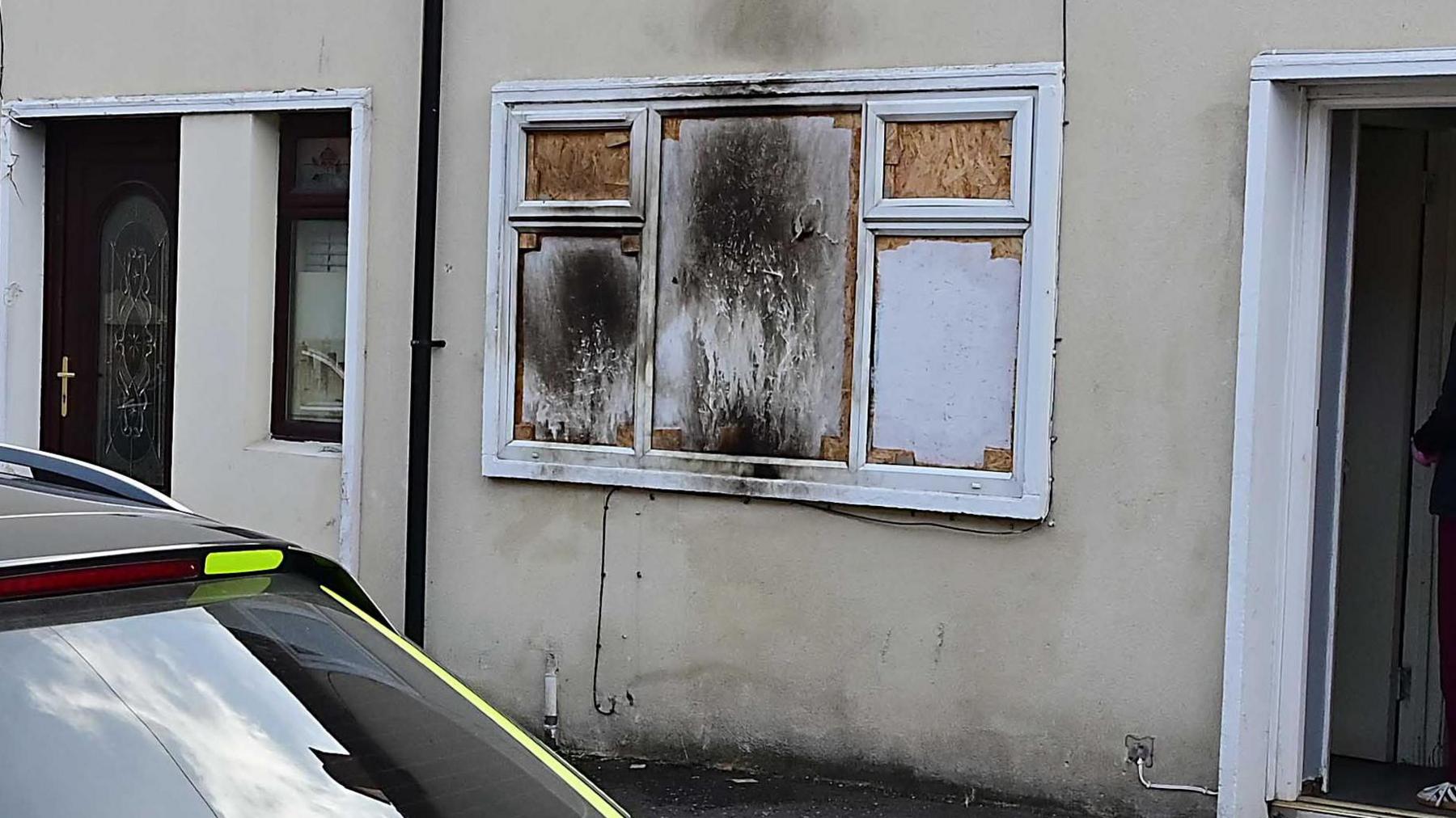 A house with windows boarded up after an arson attack.