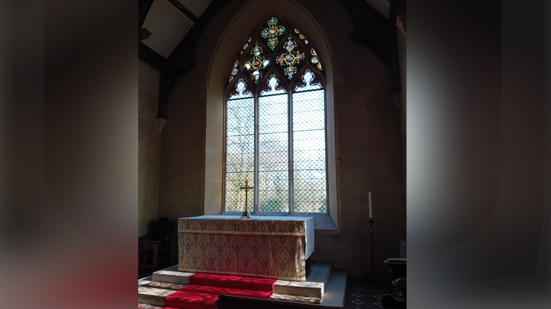 A view of a church window inside St Mary's Church. The large altar sits in front of the window with steps leading up to it.