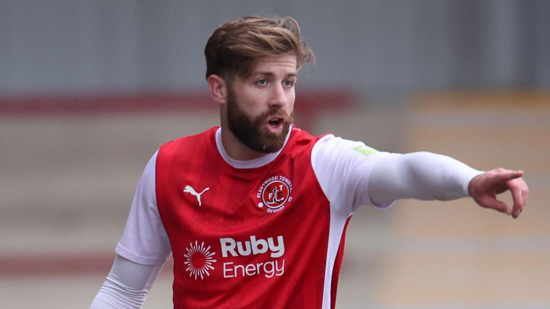 Shaun Rooney pointing with his left hand at a Fleetwood team-mate