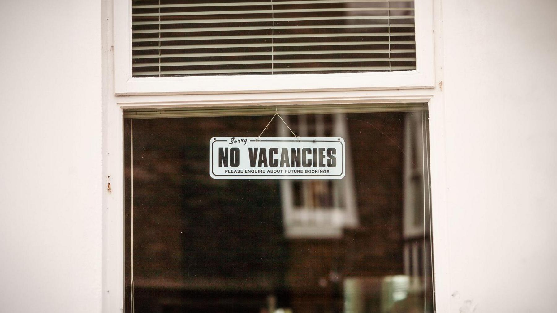 Black and white 'no vacancies' sign hanging up in a window.