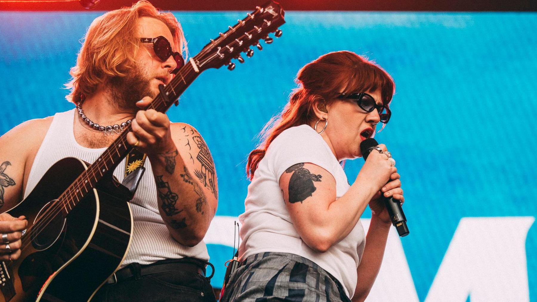 CMAT performing on stage against a blue background