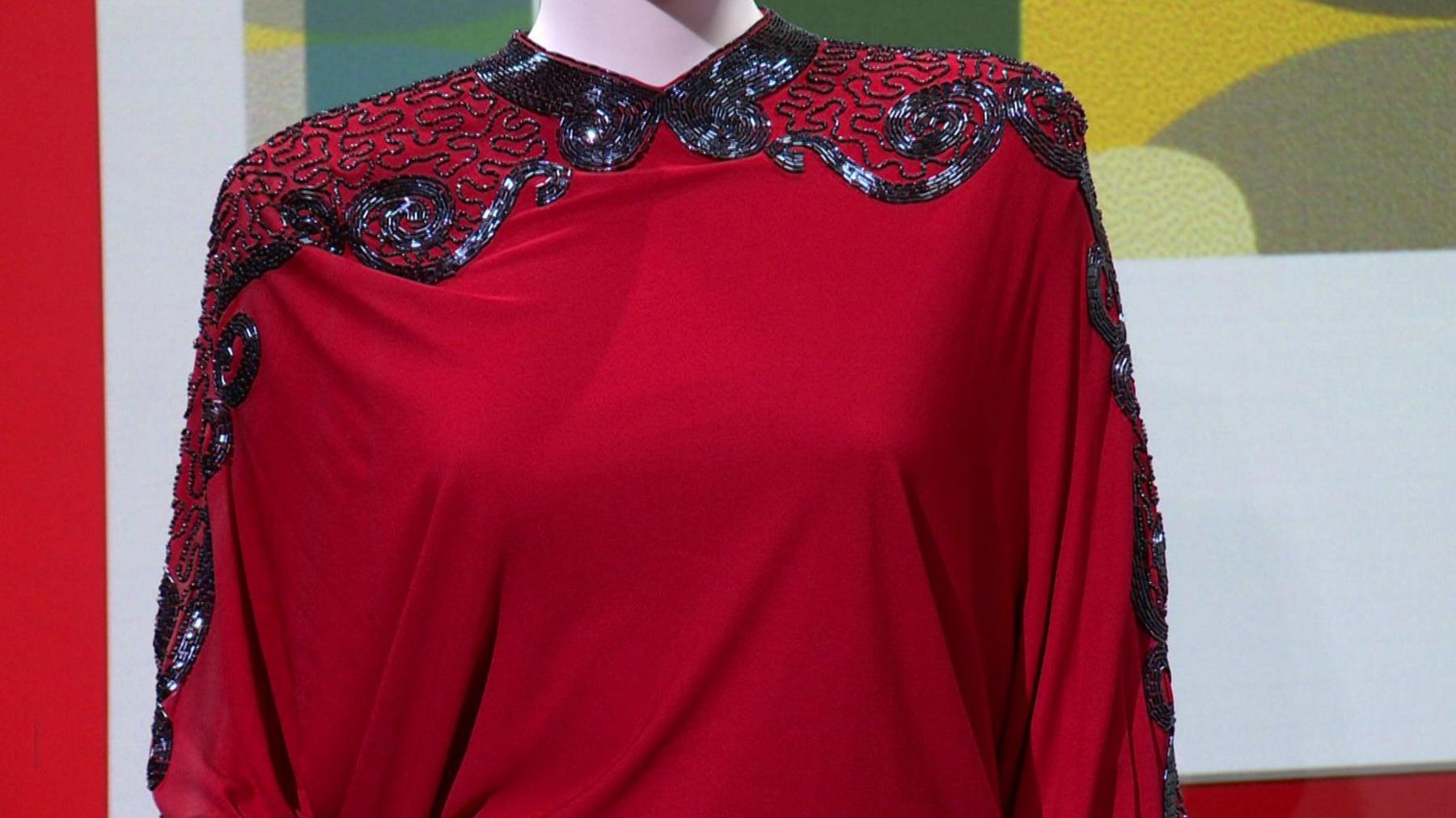 A red jumpsuit with beads in a geometric pattern on its shoulders and sleeves.