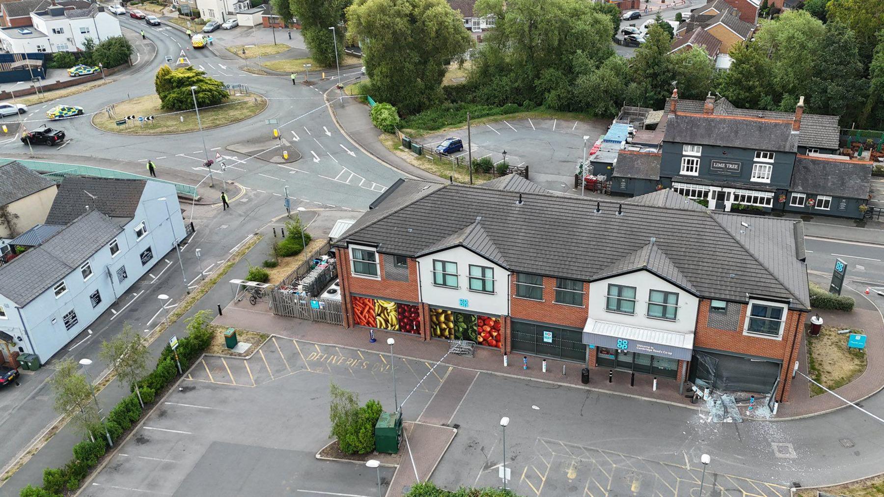 An aerial view of the Co-op store in Cambridge Road Whetstone showing its frontage damaged and a police cordon in the area.
