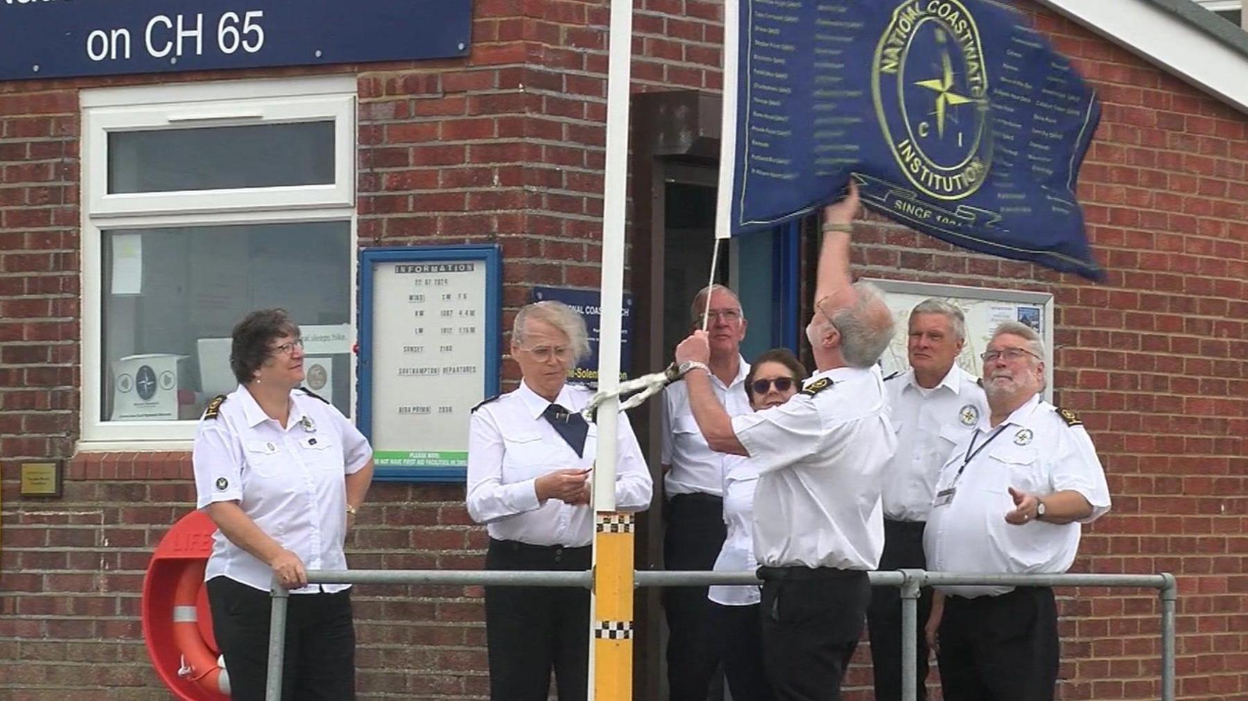 A group of NCI volunteers hoisting the NCI flag