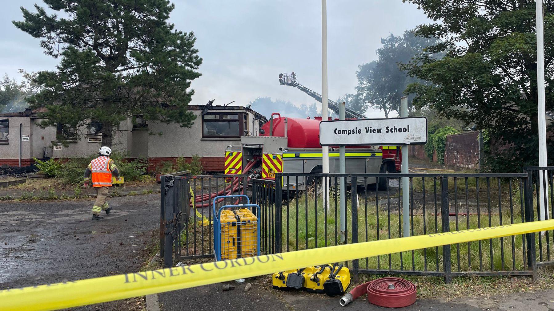 A fire engine by a burnt out building behind a cordon. A sign reads "Campsie View School"