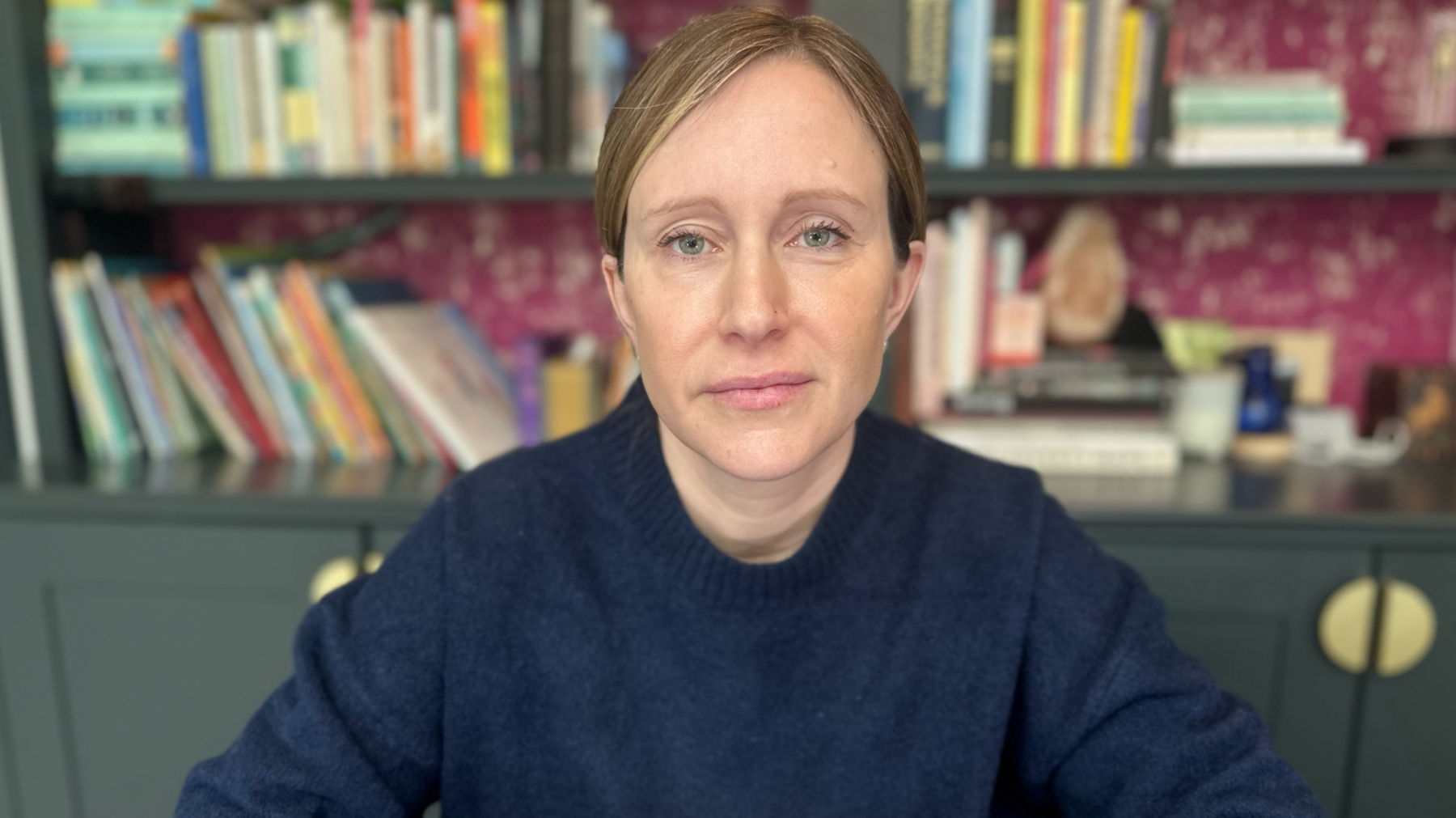 Dr Erin Sanders-McDonagh sat in a room in front of a large book case