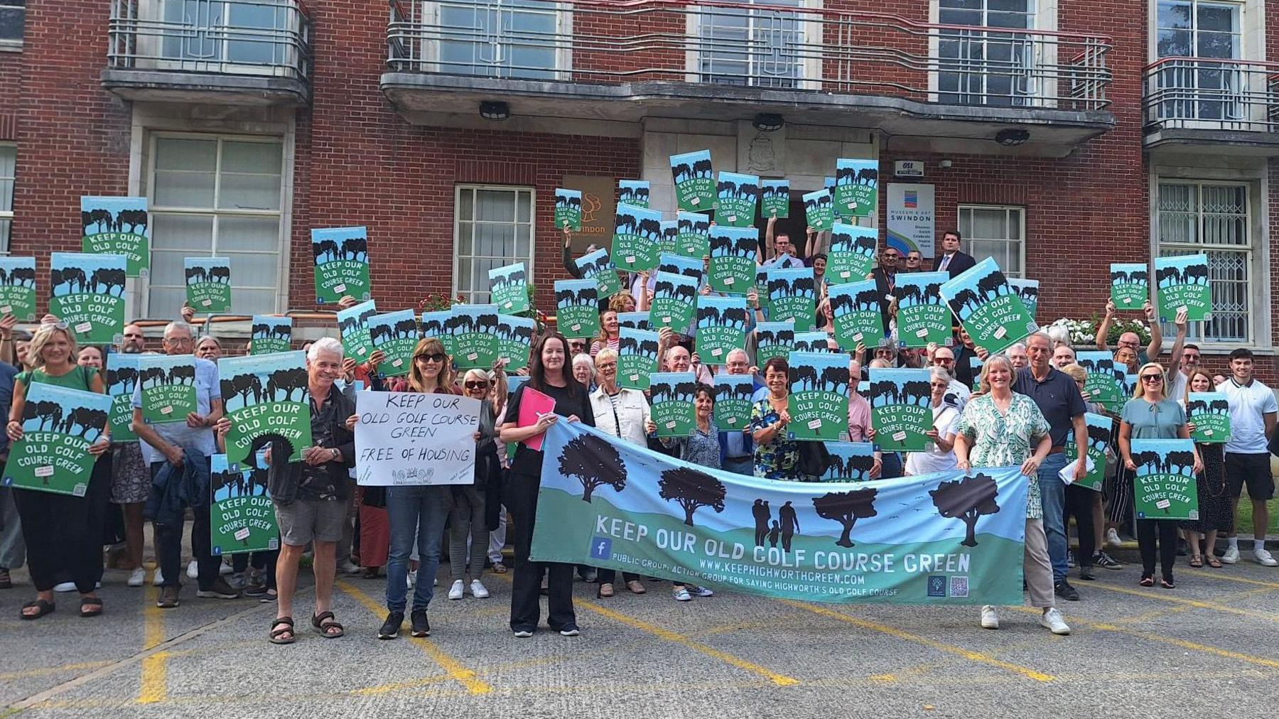 Dozens of people holding  keep our golf course placards and banners outside Swindon council offices