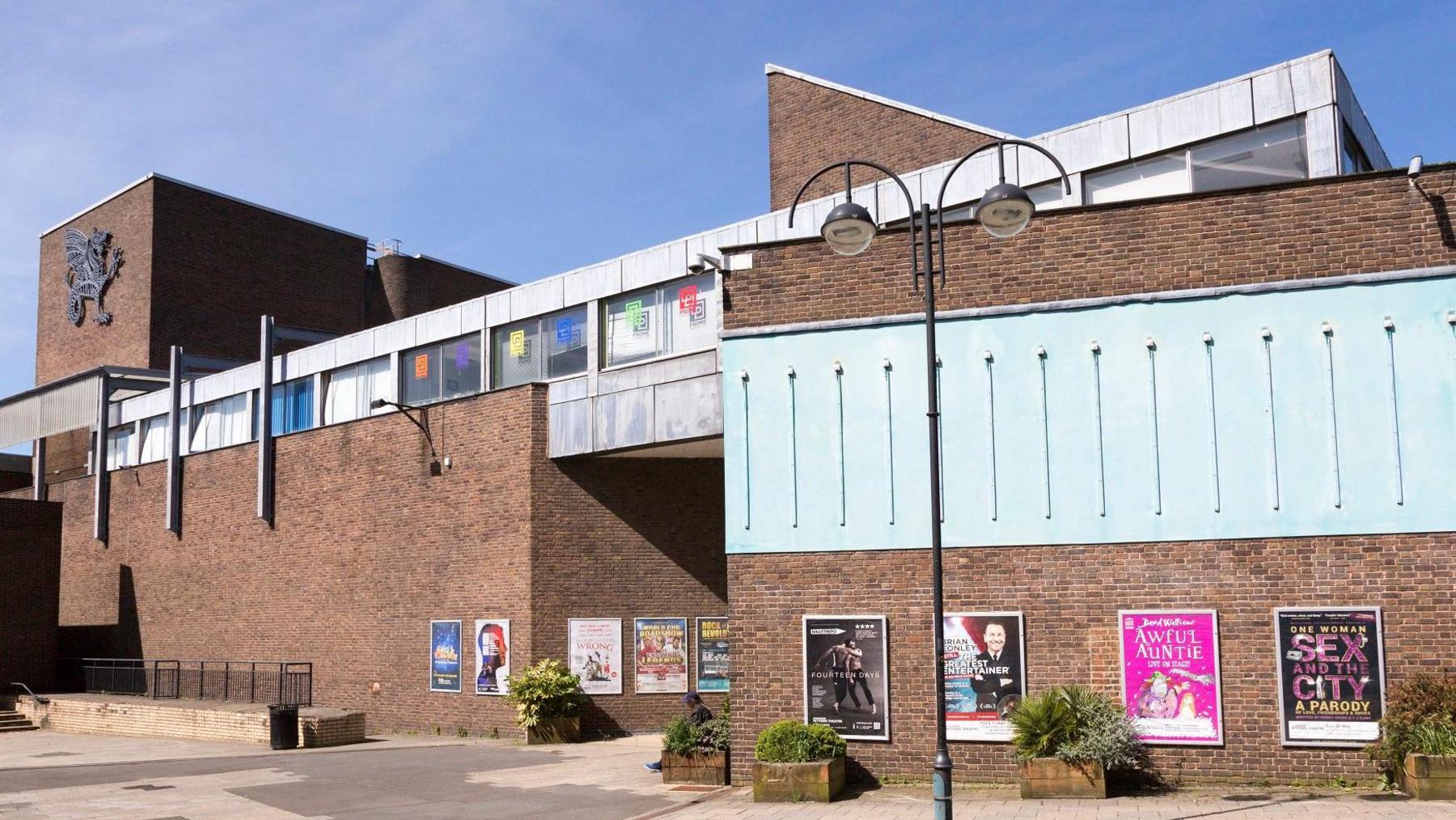 An external shot of the Wyvern Theatre showing posters for upcoming shows and the main entrance