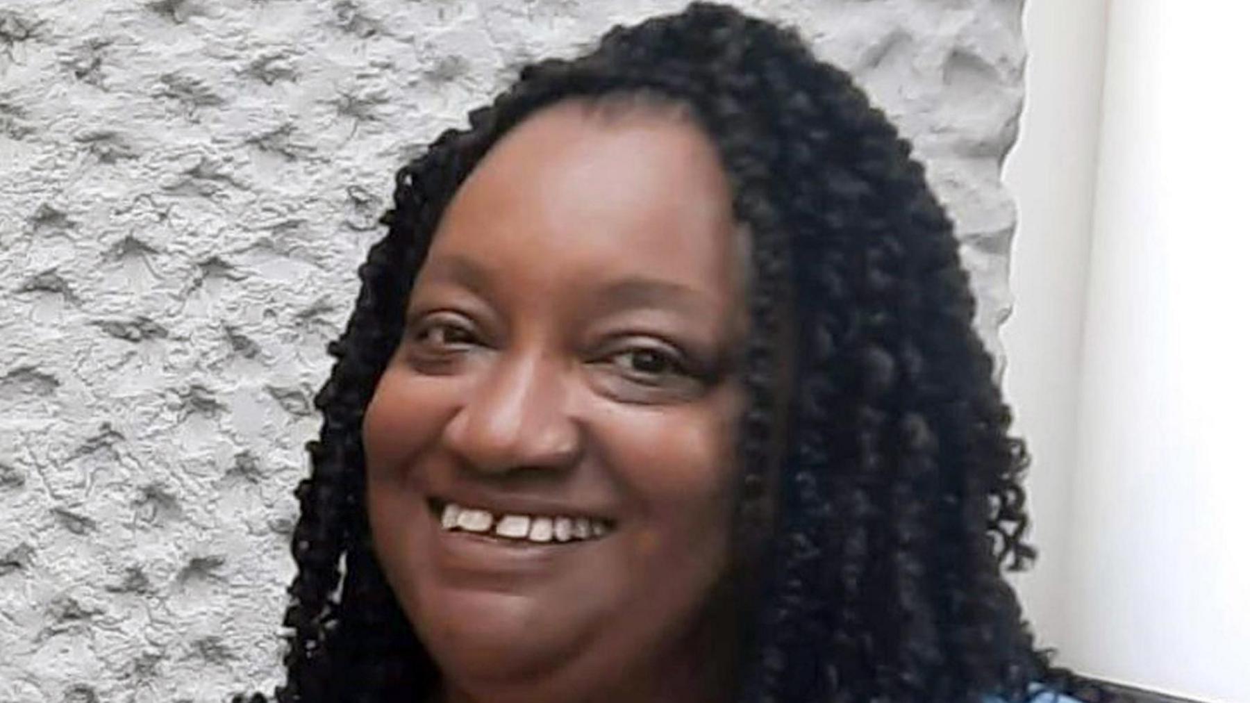 Marcia Grant smiles at the camera. She has long black curly hair.