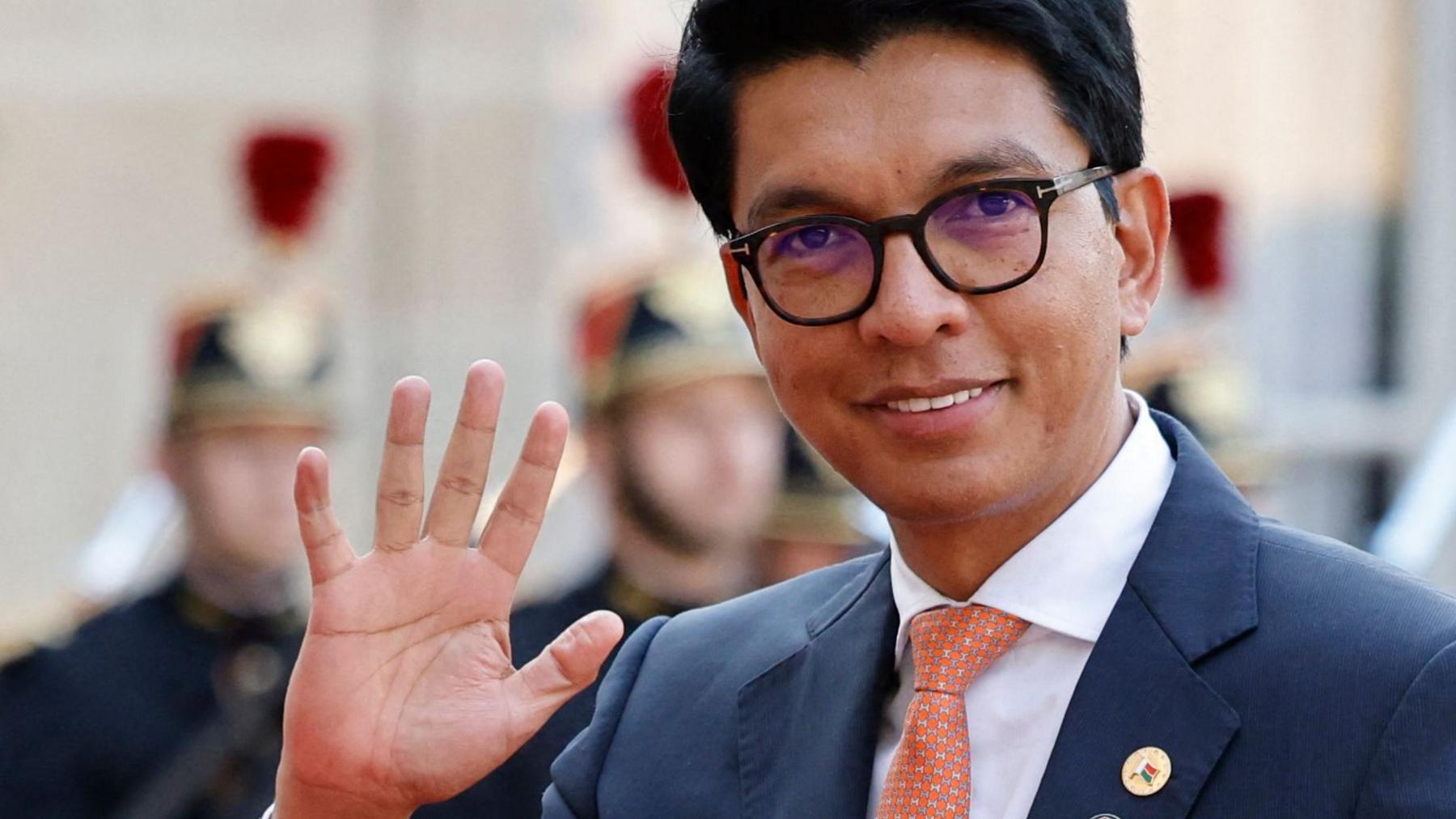 Andry Rajoelina waves in France in 2023. He is wearing a smart suit and classes.